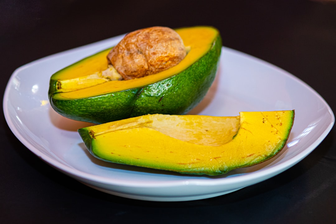 Avocado - a white plate topped with a cut in half avocado