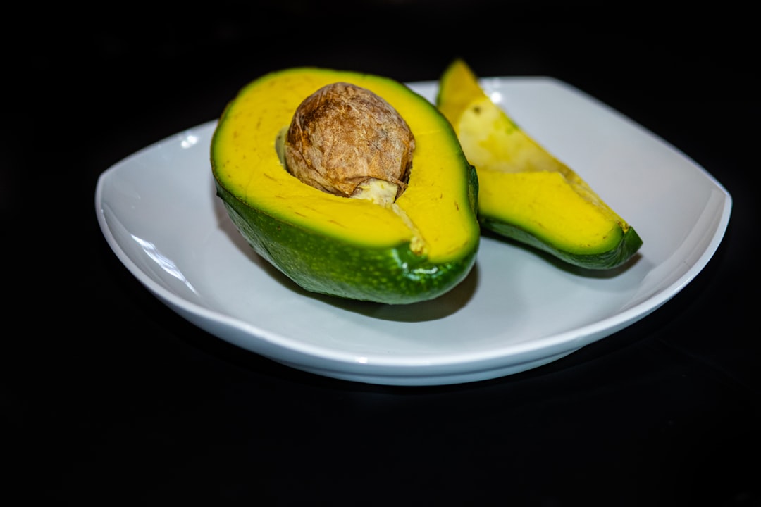 Avocado - a white plate topped with a cut in half avocado