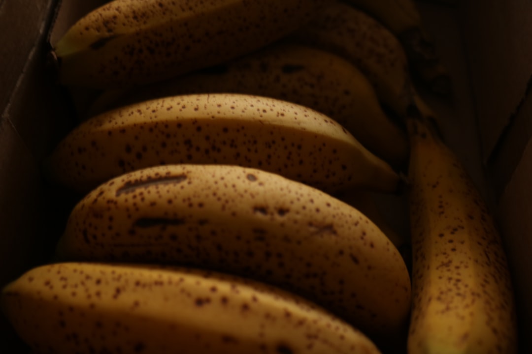 Banana - Several ripe bananas with brown spots in a box