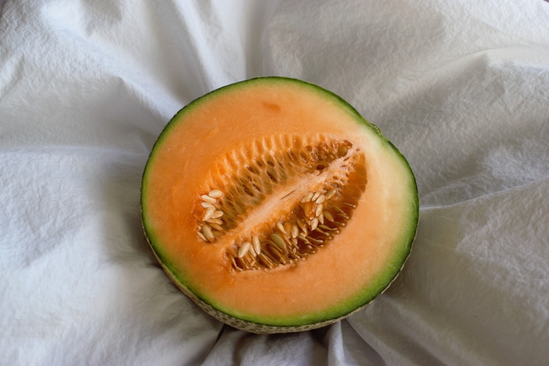 Cantaloupe - a cut in half melon sitting on top of a white cloth