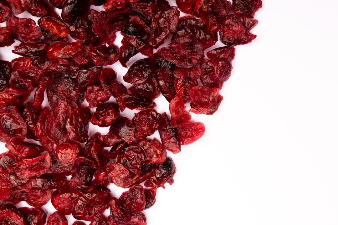 Cranberry - Dried cranberries scattered on a white surface.
