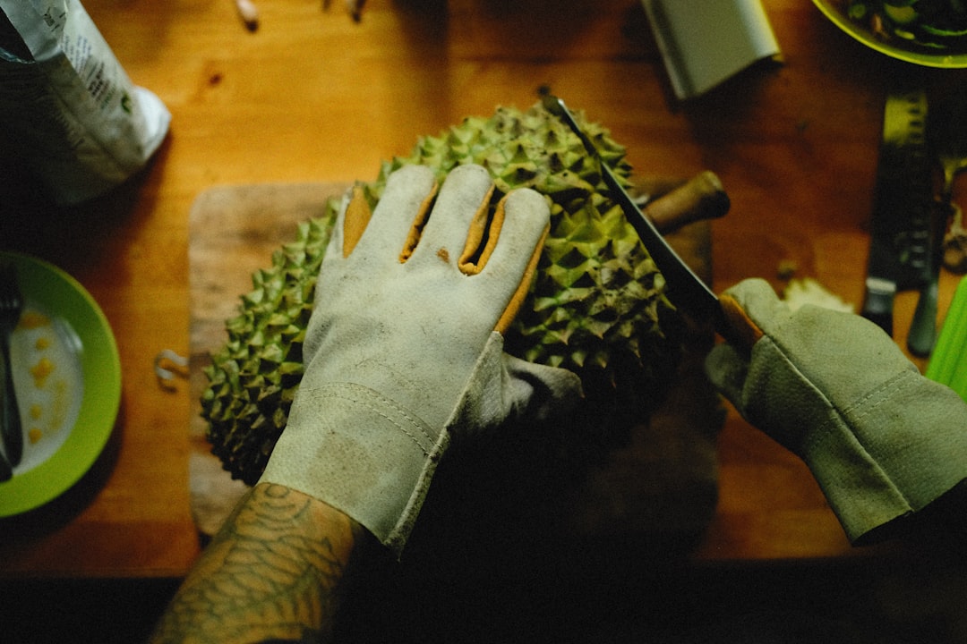 Durian - a person cutting a durian fruit on a cutting board