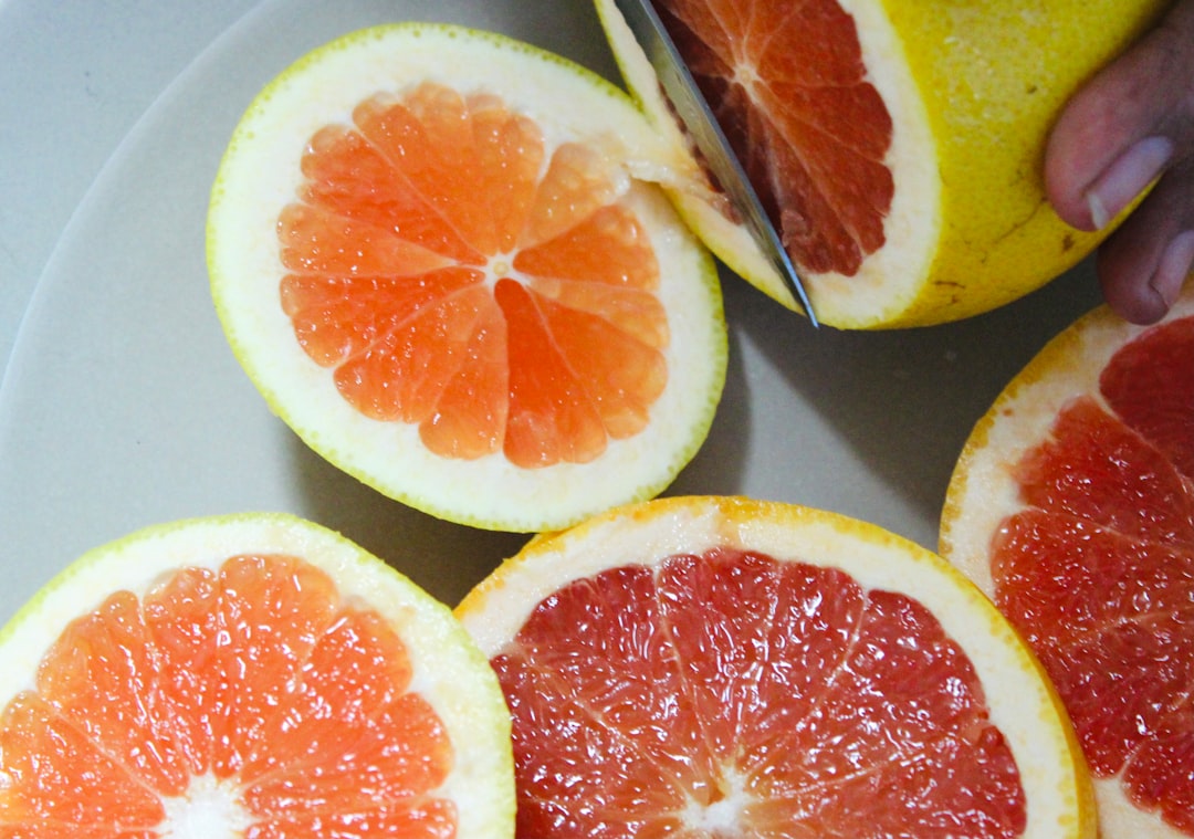 Grapefruit - a person cutting up a grapefruit on a plate