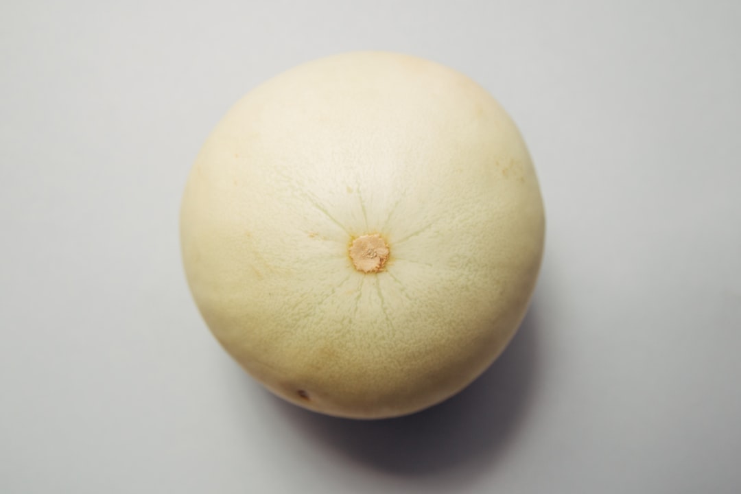 Honeydew - round brown fruit placed on white surface