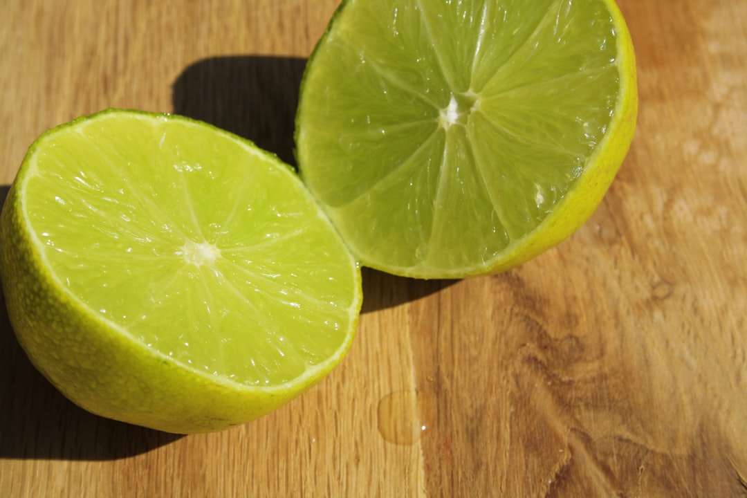 Lime - A couple of limes sitting on top of a wooden table