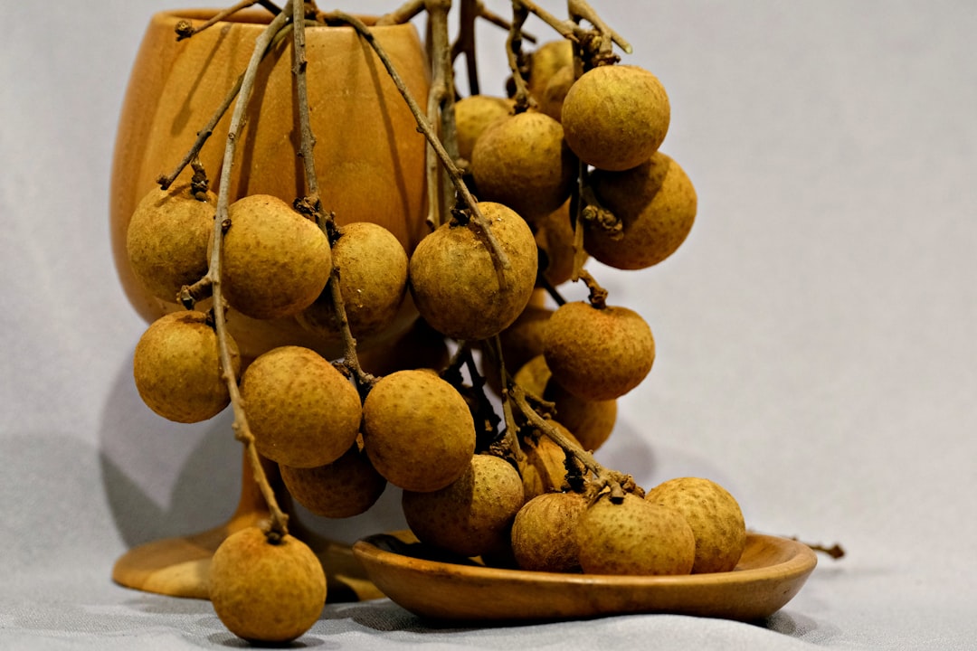 Longan - Fresh longan fruits hanging from branches on a plate.