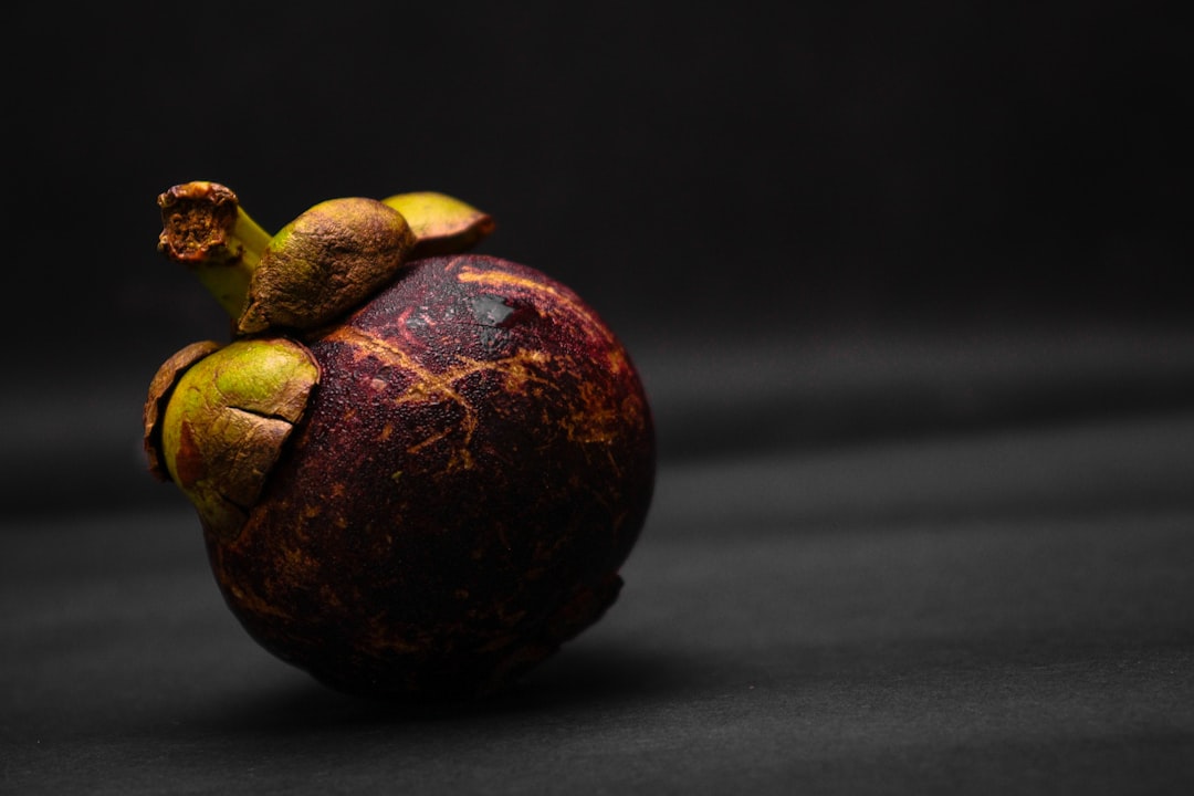 Mangosteen - a close up of a fruit on a black background