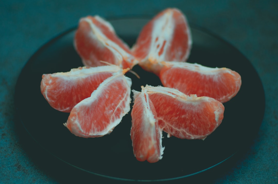 Pomelo - sliced red fruit on black plate